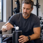 Man over 40 preparing creatine with water near dumbbells after strength training